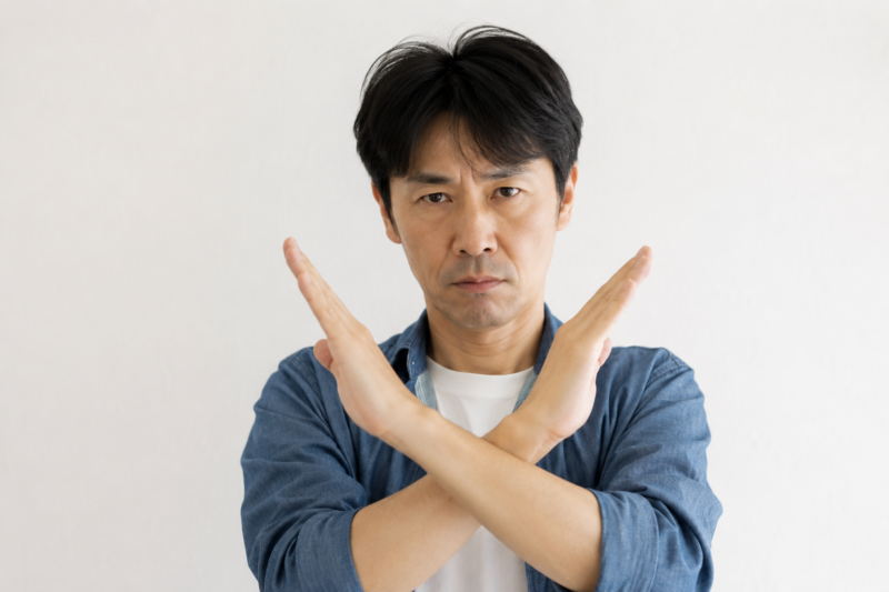 両手でバツ印を作り「描かない」という意思を示す男性の写真｜副業とお金のリアルVol.16